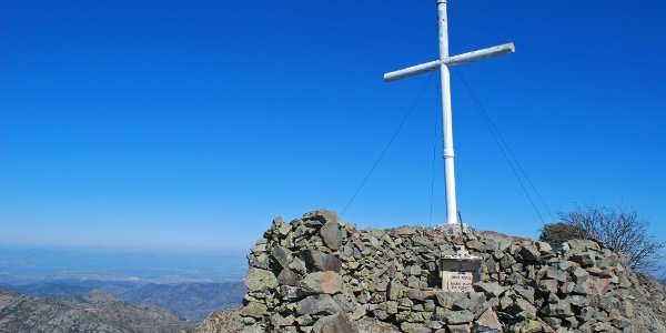 Wooden cross at the summit of Mount Papoutsa in the Troodos Mountains, Cyprus, standing against winter skies and strong winds