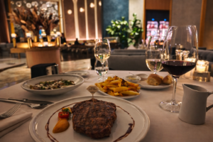 Prime Steakhouse at City of Dreams Mediterranean in Limassol, featuring a perfectly cooked steak with sides and red wine in an elegant dining setting